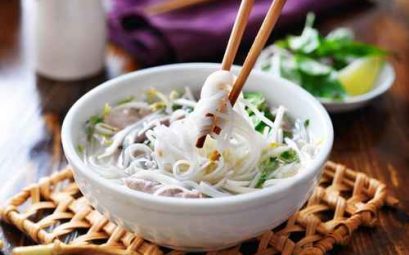 picking up noodles out of a bowl of pho